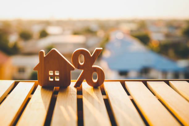 istockphoto-1483319549-612×612 Percentage and house sign symbol icon wooden on wood table. Concepts of home interest, real estate, investing in inflation.